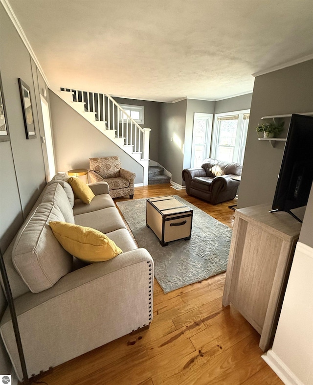 living room with stairway, baseboards, wood finished floors, and crown molding