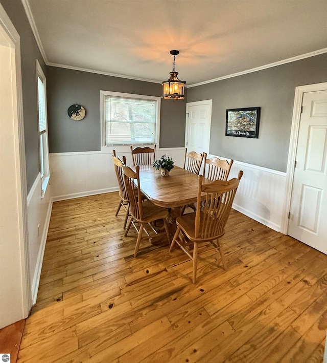 dining space featuring a chandelier, crown molding, light wood finished floors, and wainscoting