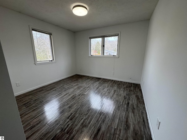 unfurnished room with baseboards, dark wood-style flooring, and a textured ceiling