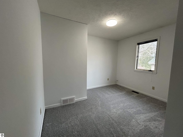 carpeted empty room featuring baseboards, visible vents, and a textured ceiling