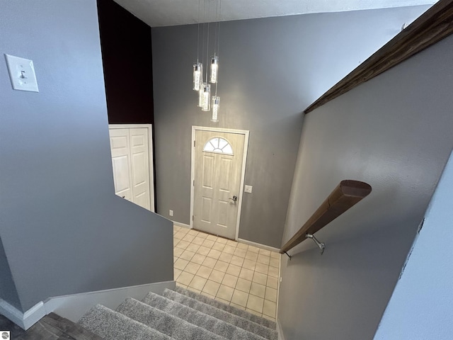 foyer entrance featuring baseboards, a towering ceiling, stairs, and tile patterned flooring