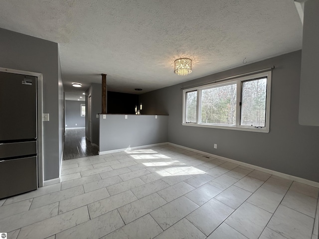 spare room with baseboards and a textured ceiling