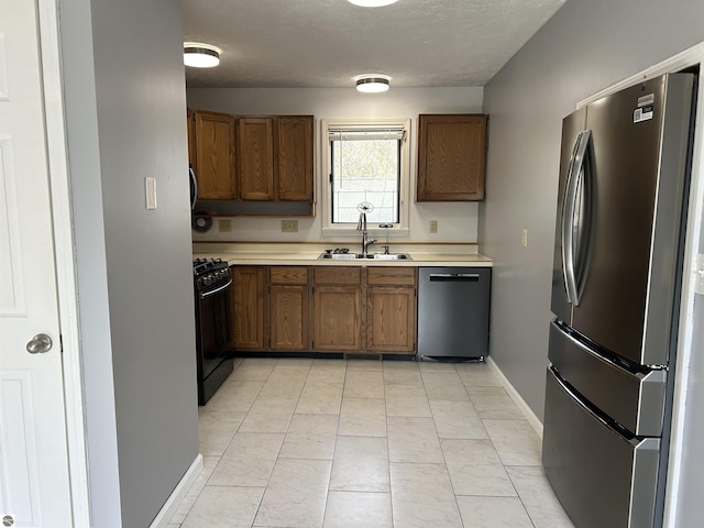 kitchen featuring light countertops, brown cabinets, appliances with stainless steel finishes, and a sink