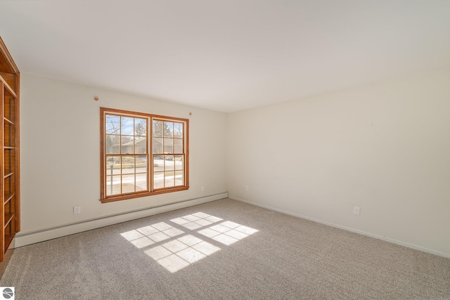 spare room featuring a baseboard heating unit, baseboards, and carpet