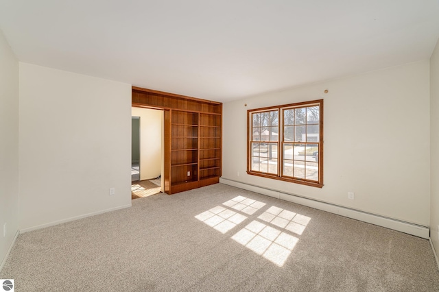 carpeted empty room with built in features, baseboards, and baseboard heating