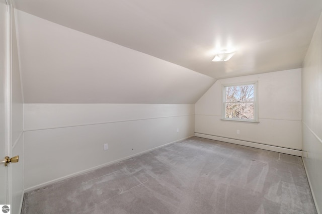 additional living space with lofted ceiling, baseboard heating, and carpet