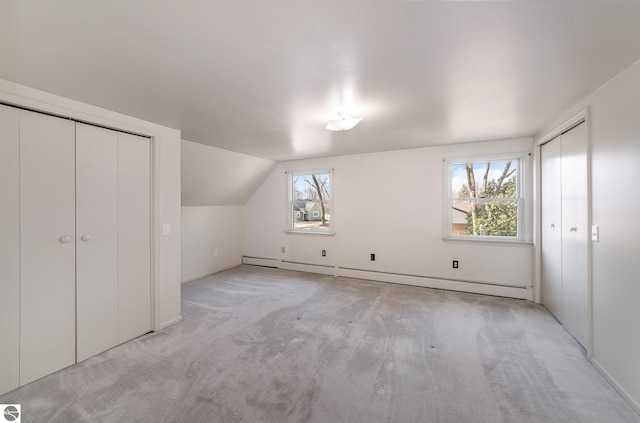 bonus room featuring light carpet, baseboard heating, and a healthy amount of sunlight