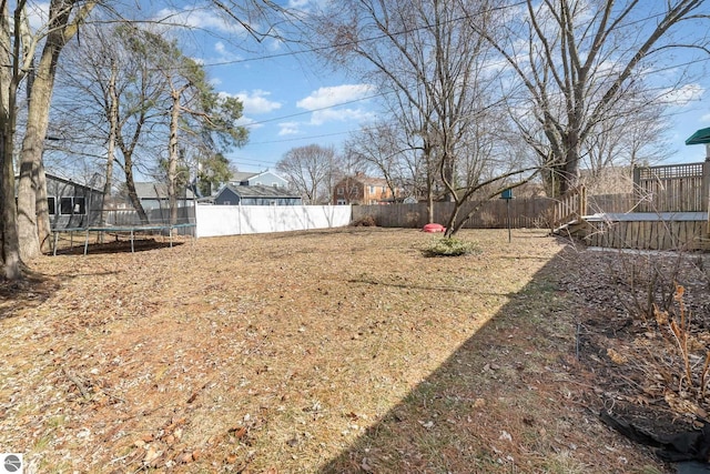 view of yard with a trampoline and a fenced backyard