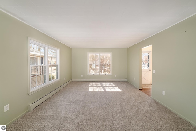 empty room with a baseboard heating unit, plenty of natural light, light colored carpet, and baseboards