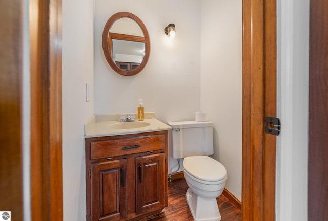 bathroom featuring toilet, vanity, baseboards, and wood finished floors