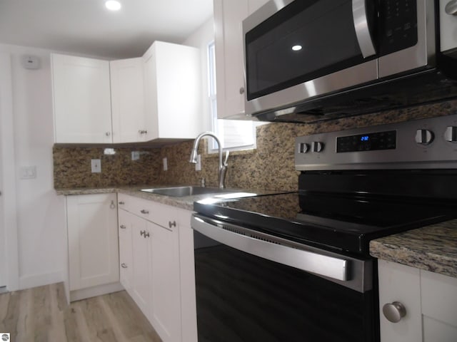 4177 Seminole St, Gladwin, MI 48624 - kitchen featuring stainless steel appliances, light wood-style floors, white cabinets, tasteful backsplash, and a sink
