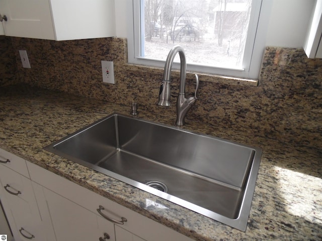 4177 Seminole St, Gladwin, MI 48624 - kitchen view of a sink, white cabinetry, decorative backsplash, and light stone countertops