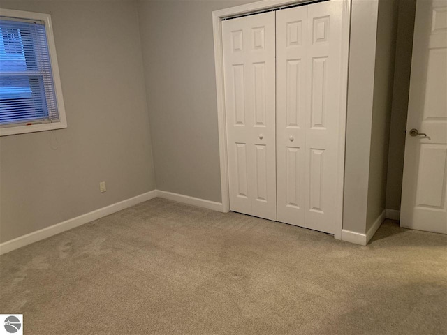 unfurnished bedroom with baseboards, a closet, and light carpet