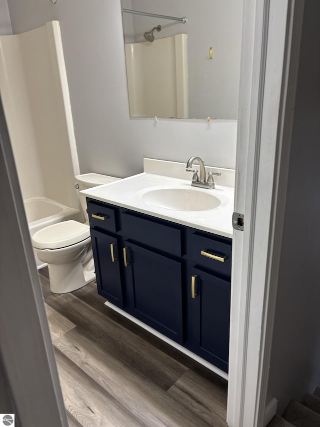 bathroom featuring toilet, vanity, shower / bathtub combination, and wood finished floors