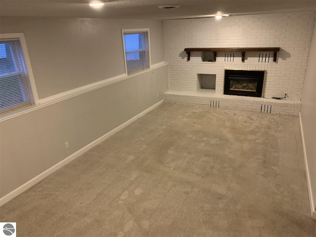 unfurnished living room featuring baseboards, carpet floors, a textured ceiling, and a fireplace