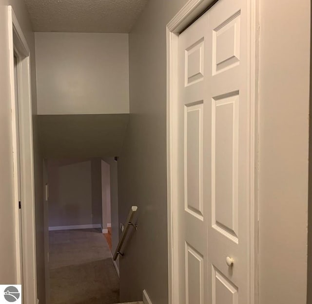 stairway with baseboards and a textured ceiling