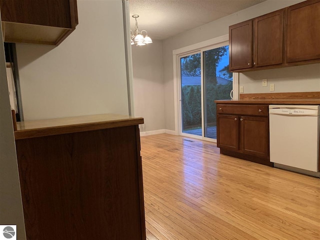 kitchen with baseboards, light wood-style flooring, white dishwasher, dark brown cabinetry, and a notable chandelier