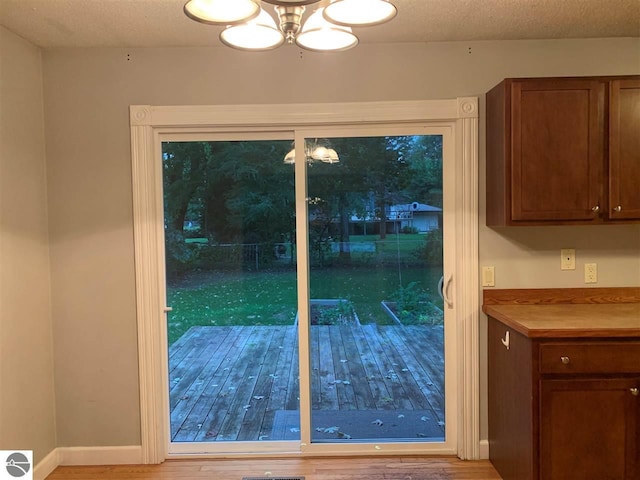 doorway to outside featuring visible vents, a textured ceiling, baseboards, and wood finished floors