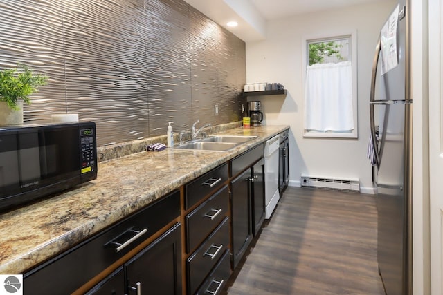 kitchen featuring a baseboard heating unit, black microwave, freestanding refrigerator, white dishwasher, and a sink