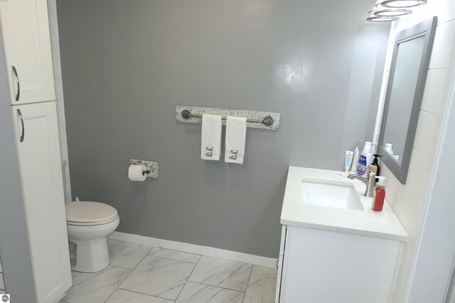 5661 Golfridge Rd, Alma, MI 48801 - bathroom featuring baseboards, toilet, marble finish floor, and vanity