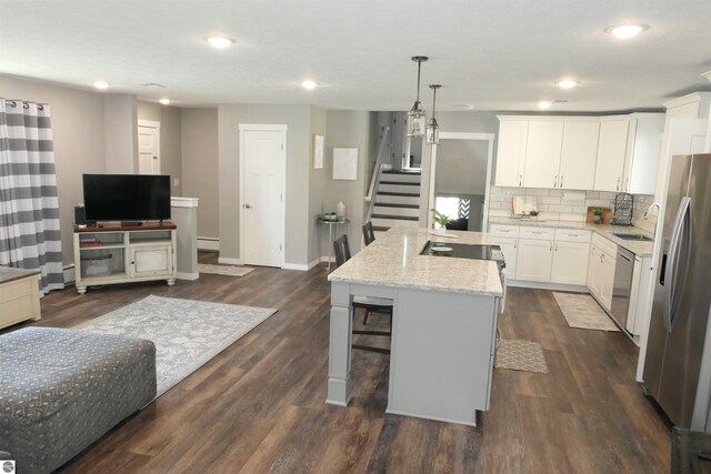 5661 Golfridge Rd, Alma, MI 48801 - kitchen featuring light stone countertops, a kitchen island, appliances with stainless steel finishes, white cabinetry, and backsplash