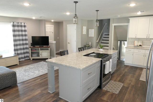 5661 Golfridge Rd, Alma, MI 48801 - kitchen with dark wood finished floors, a breakfast bar, stainless steel electric stove, white cabinets, and open floor plan
