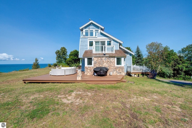 4781 E Golfview Dr, Leland, MI 49654 - rear view of house featuring stone siding, a lawn, outdoor lounge area, and a deck with water view
