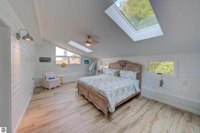 4781 E Golfview Dr, Leland, MI 49654 - bedroom with vaulted ceiling with skylight, light wood finished floors, wooden walls, and ceiling fan