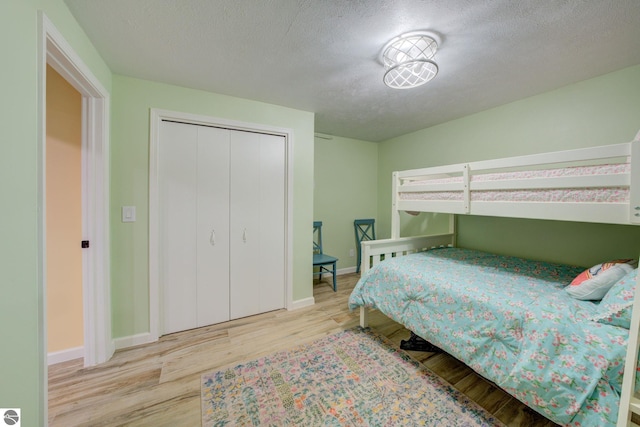 4781 E Golfview Dr, Leland, MI 49654 - bedroom featuring baseboards, wood finished floors, a textured ceiling, and a closet