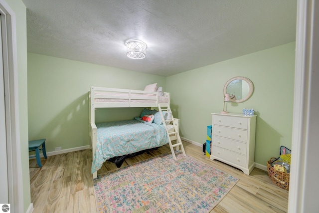 4781 E Golfview Dr, Leland, MI 49654 - bedroom with wood finished floors, a textured ceiling, and baseboards