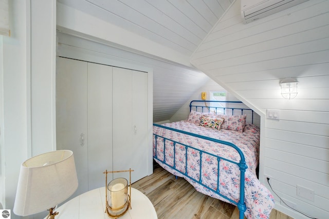 4781 E Golfview Dr, Leland, MI 49654 - bedroom featuring a wall mounted air conditioner, wooden walls, vaulted ceiling, wood finished floors, and wooden ceiling