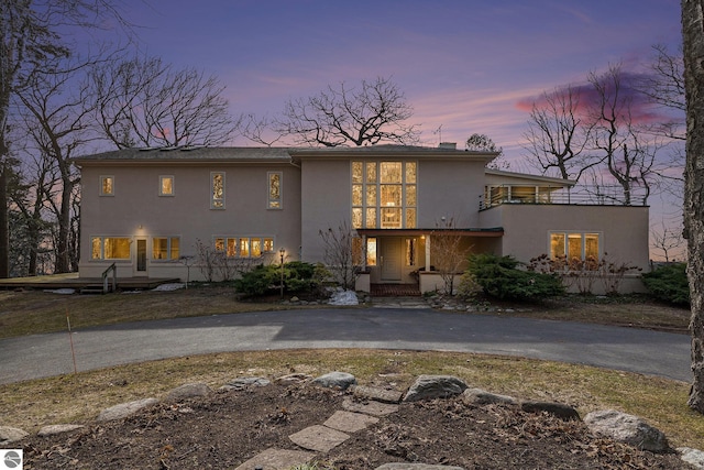 view of front of home with stucco siding, a balcony, and aphalt driveway