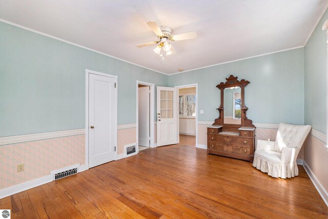 unfurnished room featuring visible vents, wallpapered walls, crown molding, ceiling fan, and hardwood / wood-style floors