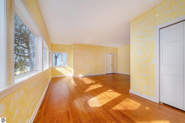 spare room with wallpapered walls, baseboards, and hardwood / wood-style floors