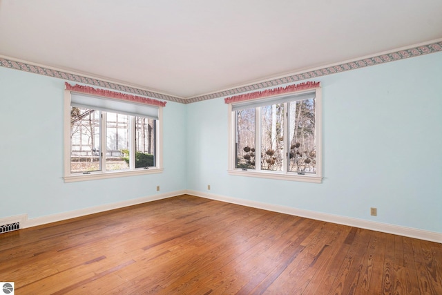 spare room with visible vents, baseboards, and hardwood / wood-style flooring