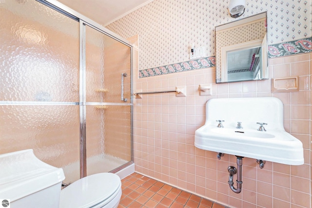 bathroom featuring a wainscoted wall, toilet, a shower stall, and wallpapered walls