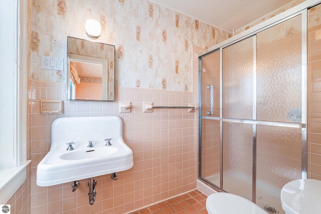 full bath featuring a wainscoted wall, toilet, a stall shower, tile walls, and wallpapered walls