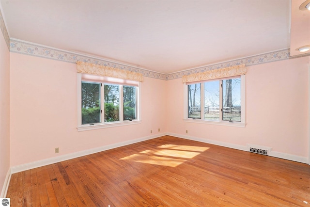 unfurnished room with visible vents, baseboards, and wood-type flooring