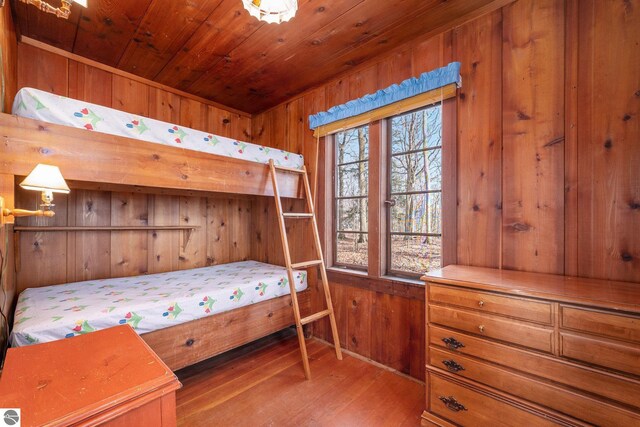 bedroom featuring wooden walls, wood ceiling, and wood finished floors
