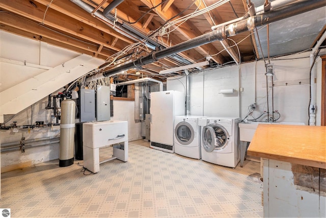 unfinished basement featuring tile patterned floors, electric panel, and washing machine and clothes dryer
