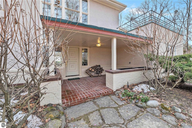 entrance to property with covered porch and stucco siding
