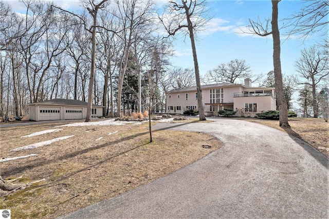view of front of property featuring stucco siding, a chimney, a detached garage, and an outdoor structure