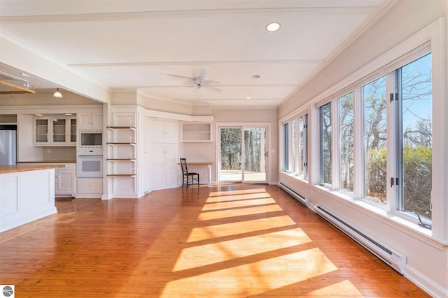 unfurnished sunroom with a baseboard heating unit and ceiling fan