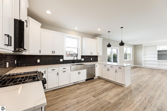 kitchen with light wood-style flooring, a sink, stainless steel dishwasher, a peninsula, and white cabinets