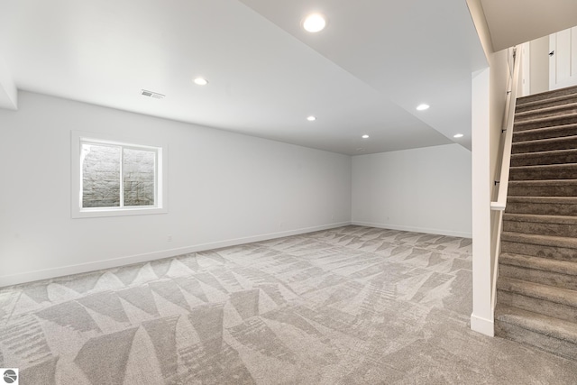 below grade area featuring recessed lighting, baseboards, light colored carpet, and stairs
