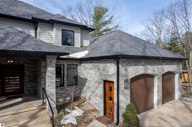 5568 Lakeview Dr, Interlochen, MI 49643 - view of front of home with an attached garage, driveway, brick siding, and a shingled roof