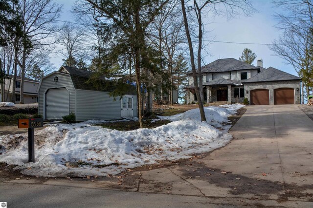 5568 Lakeview Dr, Interlochen, MI 49643 - view of front of property with an attached garage, driveway, an outdoor structure, and a gambrel roof