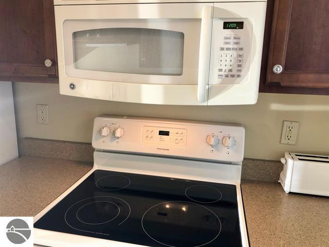5525 Golfview Ct Unit 10, Williamsburg, MI 49690 - kitchen with white appliances, a toaster, speckled floor, and dark brown cabinetry