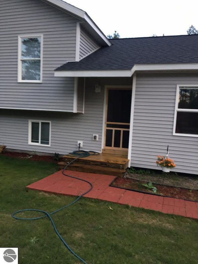back of property with a lawn and a shingled roof