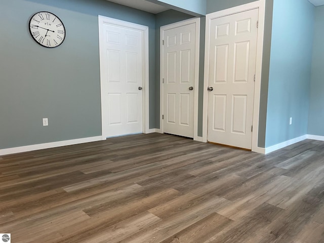 11893 Lillian Lee Dr, Interlochen, MI 49643 - unfurnished bedroom with baseboards and dark wood-style flooring